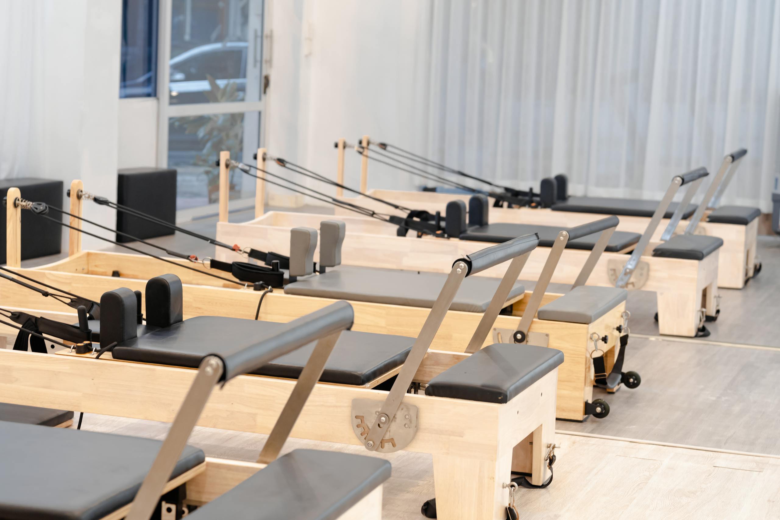 A contemporary Pilates studio equipped with multiple wooden reformers for fitness training.